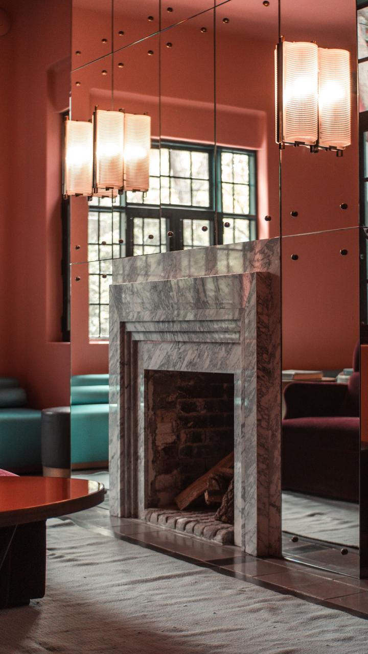 Marble fireplace surround beneath mirrors and hanging lights